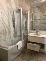 A modern bathroom with a glass-enclosed shower, a vanity with a sink, and a mirror.