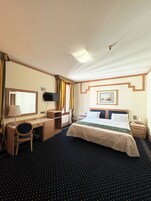 Una camera d'albergo con un letto, una scrivania, una sedia e una televisione.