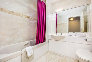 A bathroom with a bathtub, a sink, a toilet, and a mirror. - Hot-el-Apartments Canon Court (Edinburgh)