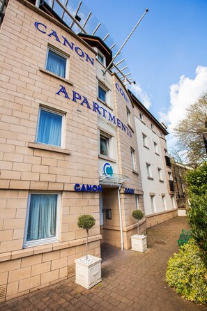 A multi-story building with "CANON APARTMENTS" signage, a small tree, and a paved entrance area. - Hot-el-Apartments Canon Court (Edinburgh)
