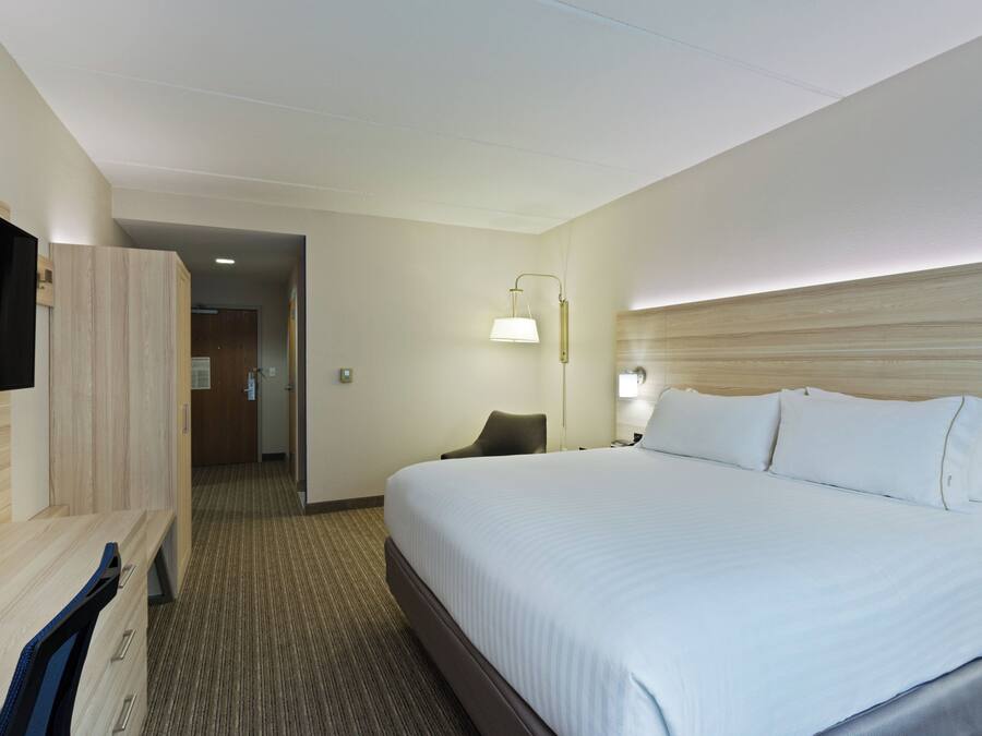 A hotel room with a bed, a TV, a desk, and a chair.