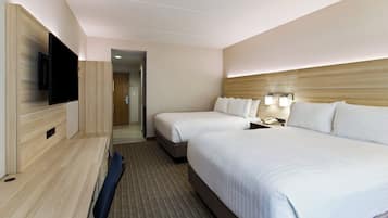 A hotel room with two beds, a television, and a desk.
