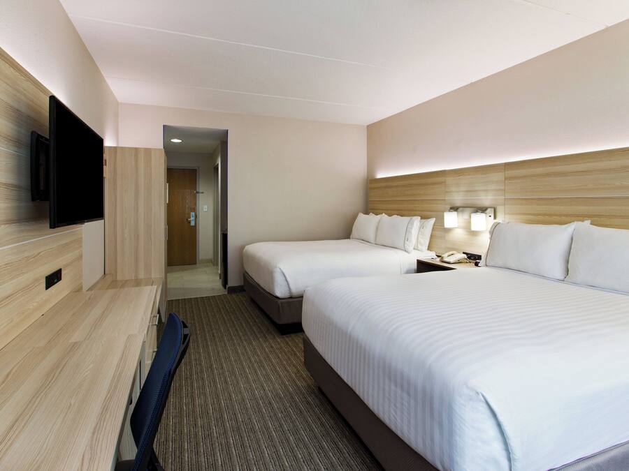 A hotel room with two beds, a television, and a desk.