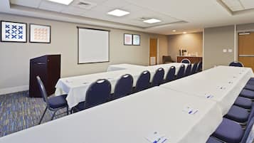 A conference room with a long table, chairs, a podium, and a projector screen.