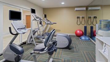 Gimnasio con cintas de correr, elíptica, pelotas de ejercicio y dispensador de agua.