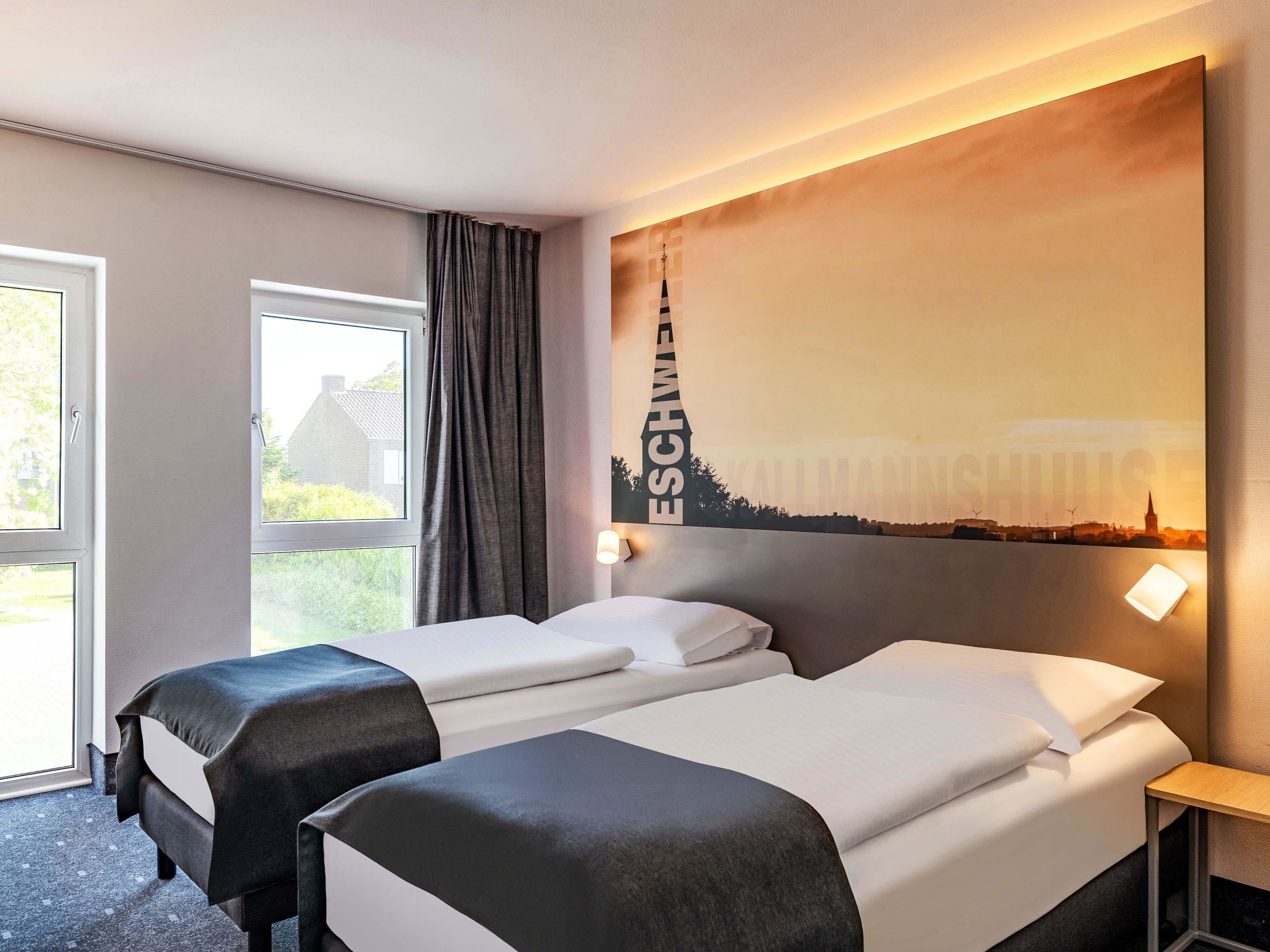 Ein Hotelzimmer mit zwei Betten, einem großen Fenster und einem Stadtbild-Wandgemälde.