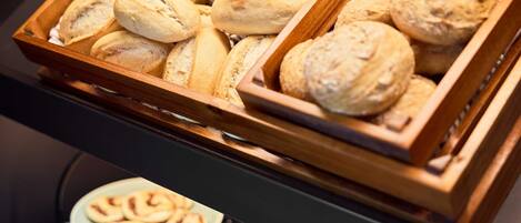 Una exhibición de productos horneados variados, como pan y pasteles, dispuestos en bandejas de madera.