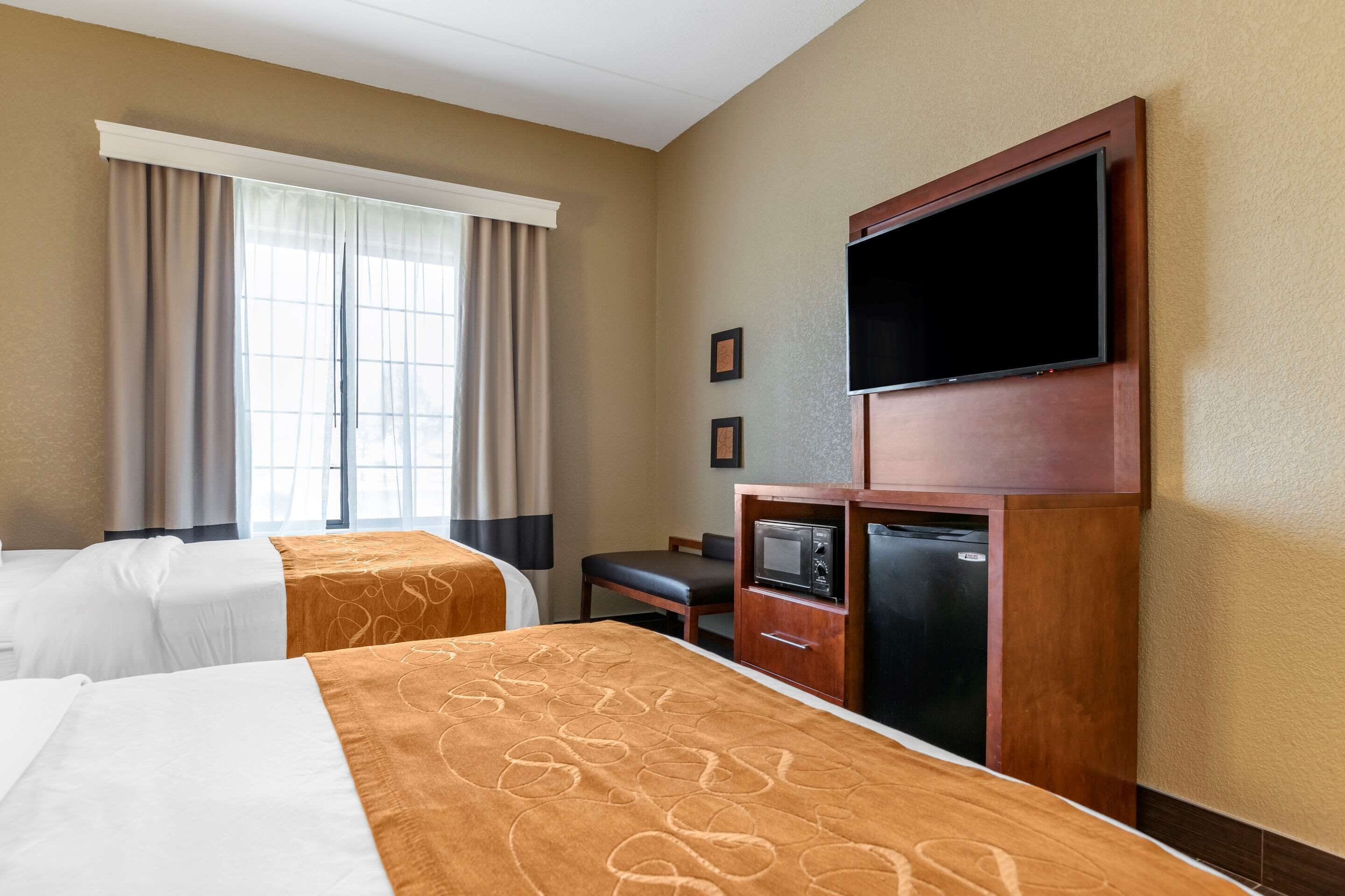 Una habitación de hotel con dos camas, televisión, microondas y un escritorio pequeño.