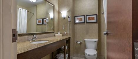 A bathroom with a sink, mirror, vanity, toilet, and shower curtain.