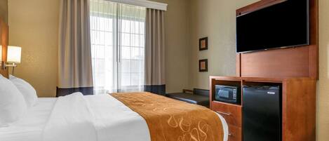 A hotel room with a bed, a television, a microwave, and a refrigerator.