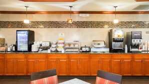 A hotel kitchen with a buffet setup, including a refrigerator, coffee machine, and various food items. - Comfort Suites Grand Rapids South (Grand Rapids)