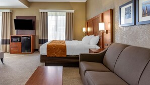 A hotel room with a bed, a TV, a desk, a couch, and a wall-mounted TV. - Comfort Suites Grand Rapids South (Grand Rapids)