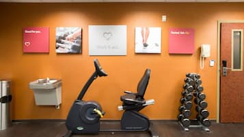 A gym with exercise equipment, a wall-mounted phone, and motivational posters.