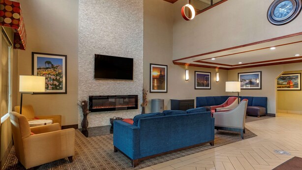 A hotel lobby with a fireplace, sofas, a TV, and framed pictures on the walls. - Comfort Suites Grand Rapids South (Grand Rapids)