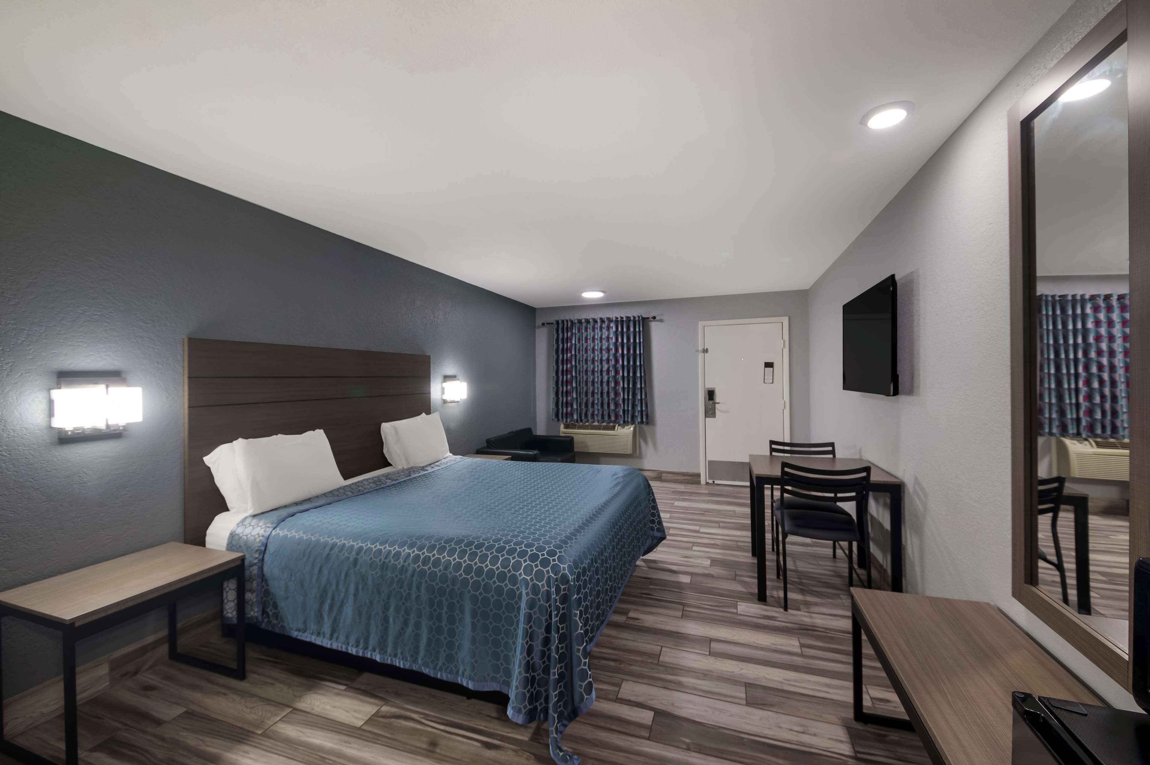 Une chambre d’hôtel comprenant un lit, des tables de chevet, un bureau, des chaises, une télévision et un miroir.