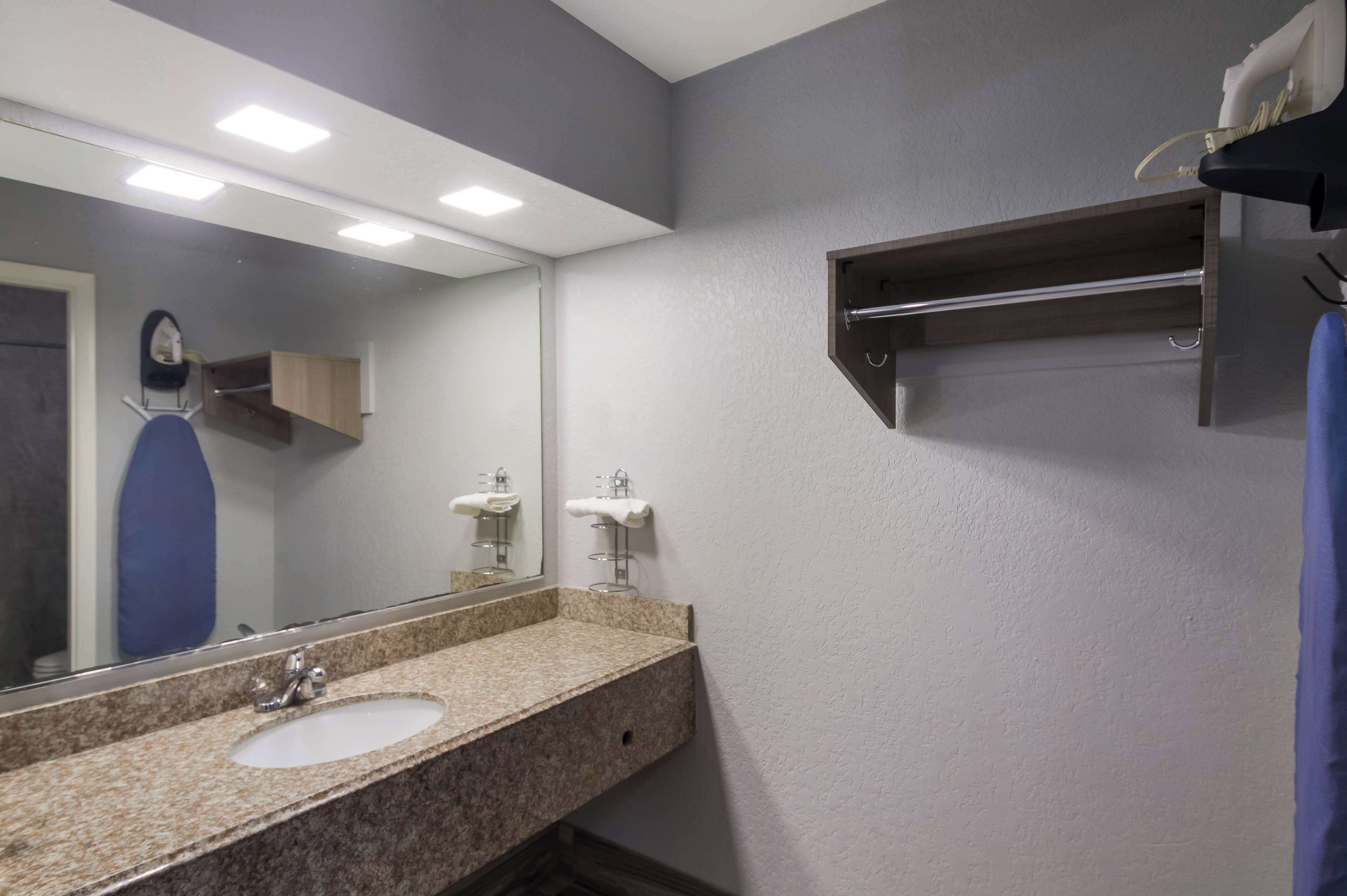 A bathroom with a granite countertop sink, a mirror, and a towel rack.