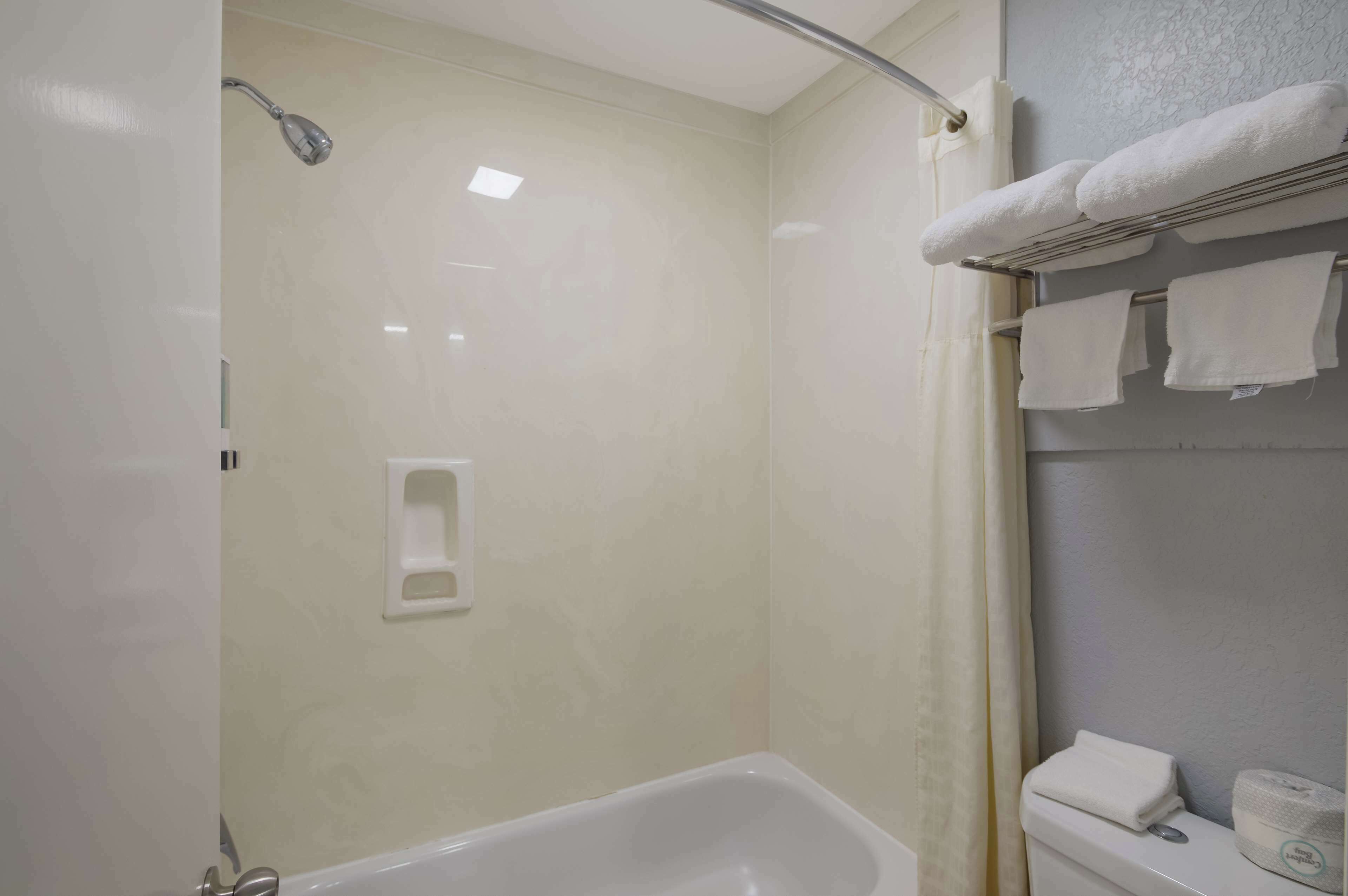 A bathroom with a shower, a bathtub, and a towel rack with multiple towels.