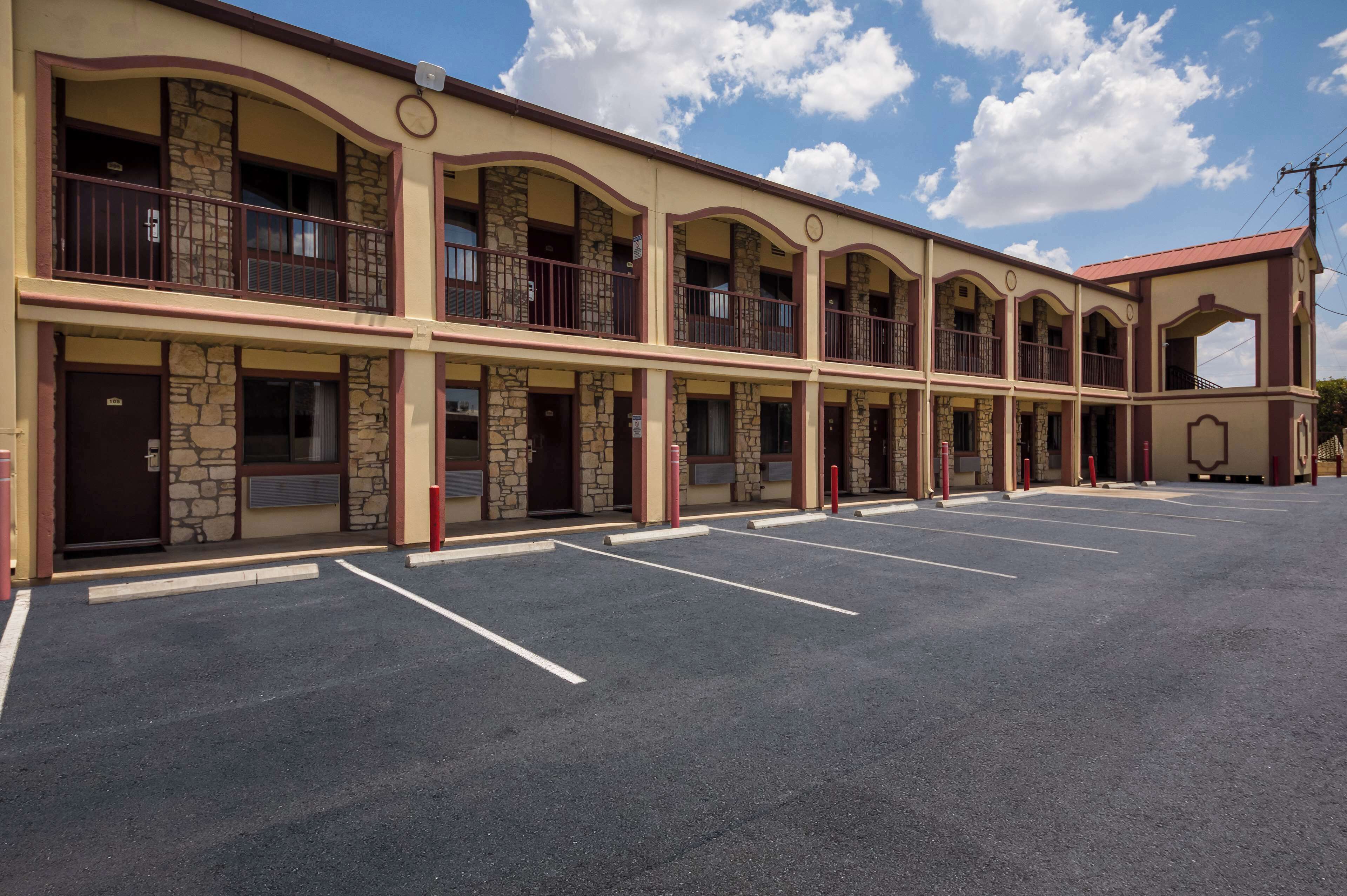 Um motel com estrutura em dois andares, várias varandas e estacionamento.