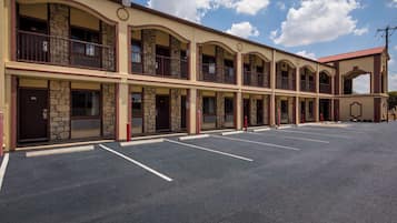 Um motel com estrutura em dois andares, várias varandas e estacionamento.
