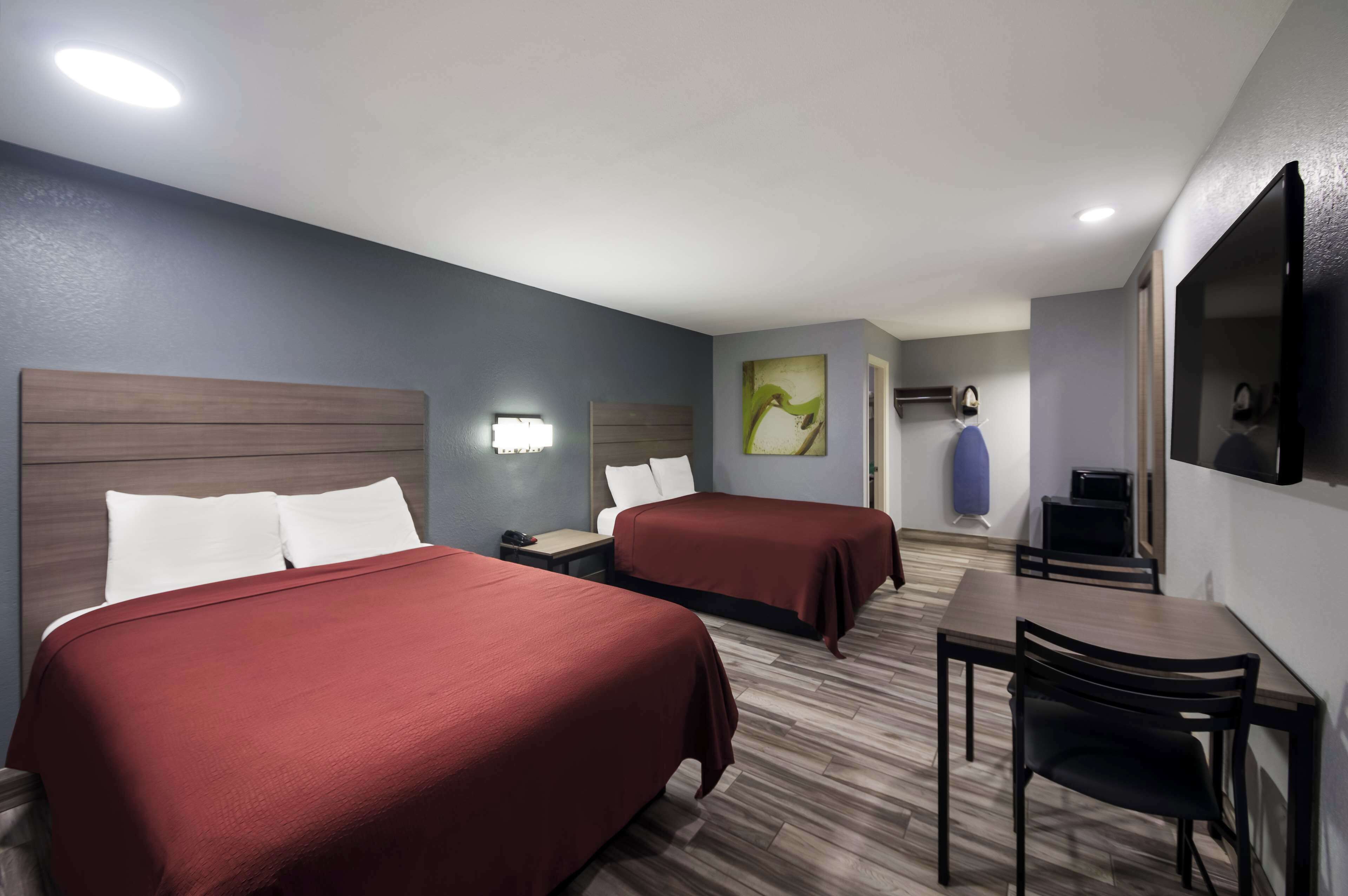 Una habitación de hotel con dos camas, un escritorio y una televisión.