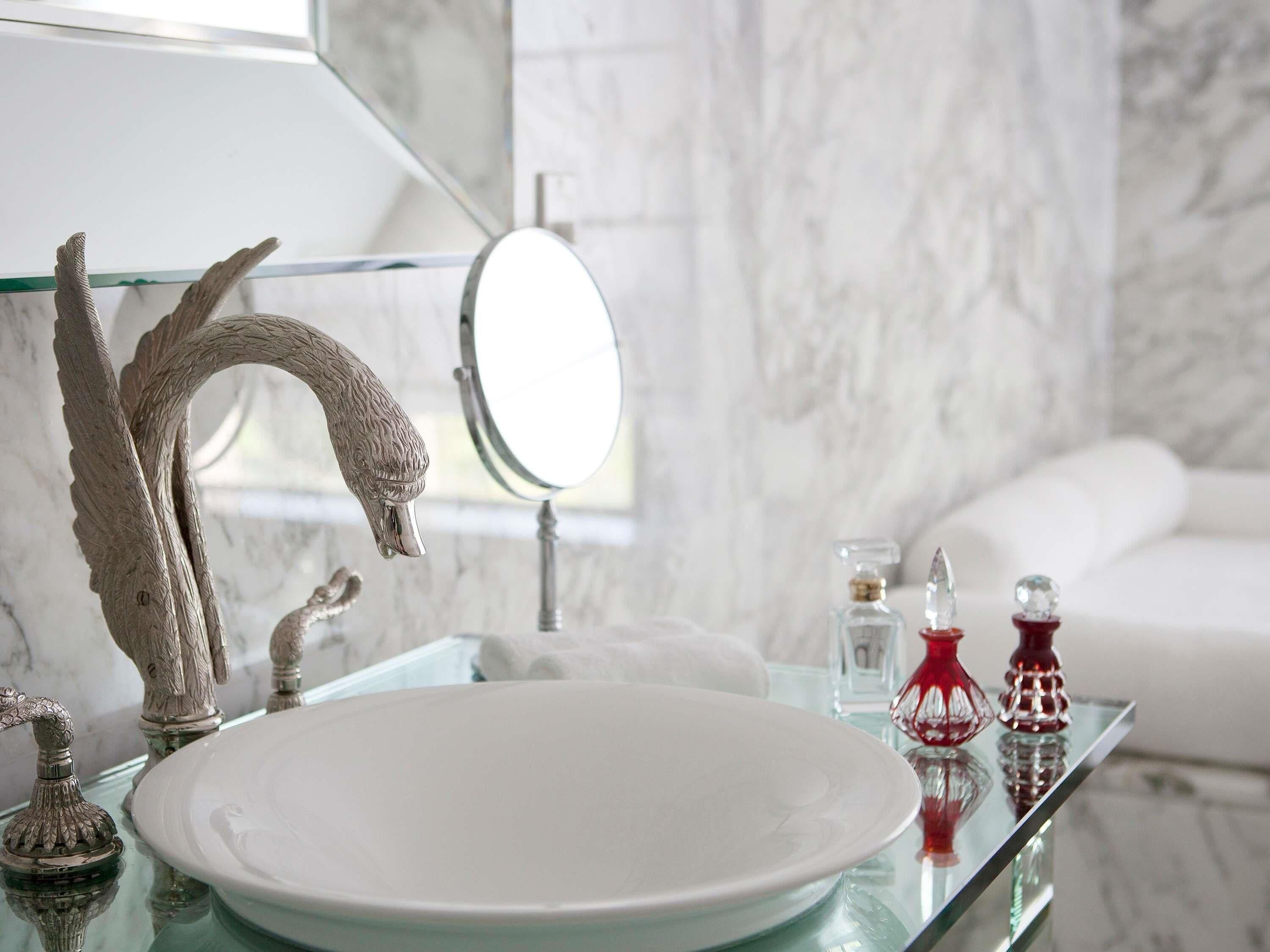 Un baño con un lavabo de vidrio, un espejo y una bañera blanca.