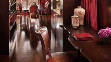 Comedor con muebles de madera, cortinas rojas y un florero con flores.