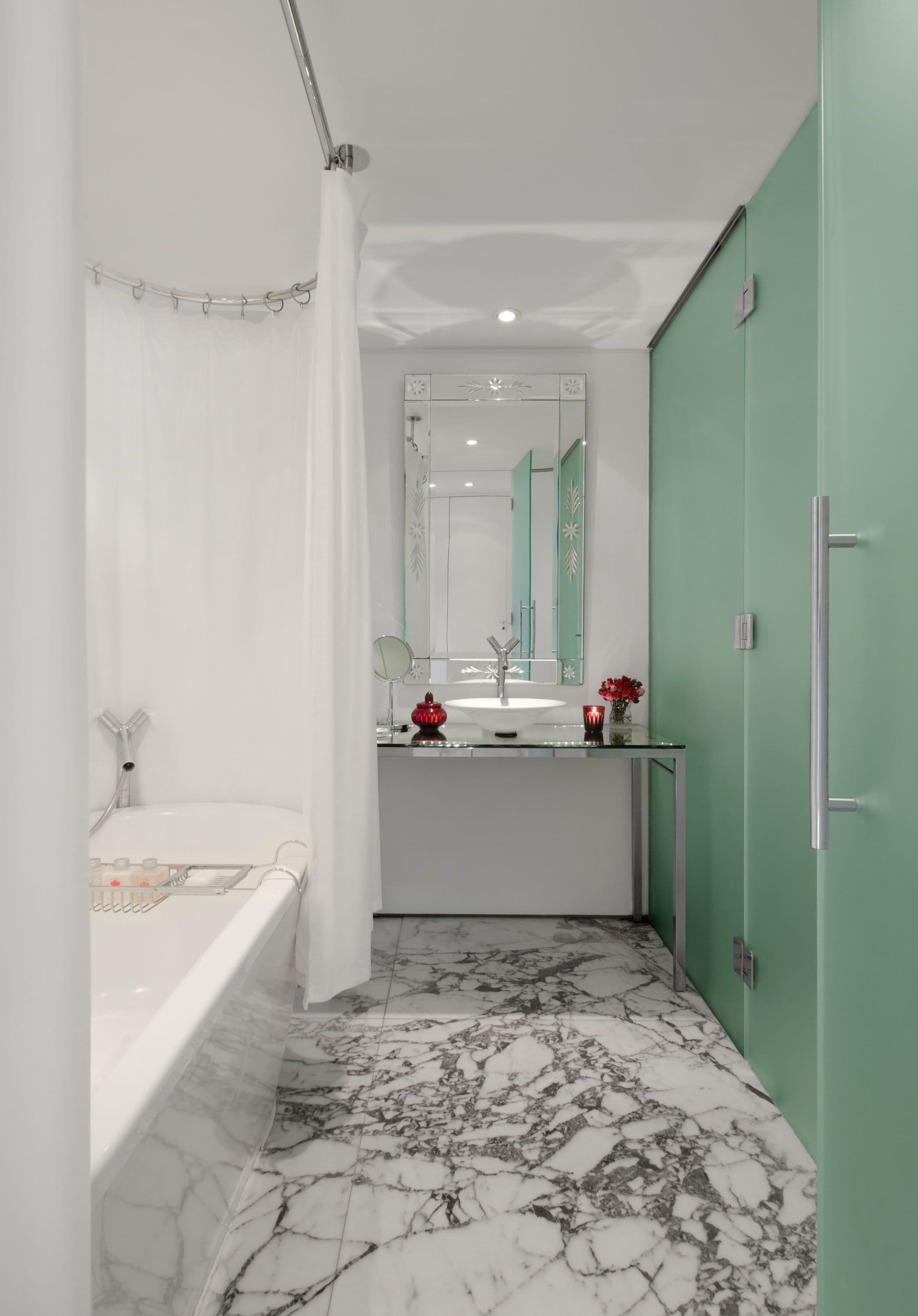 Une salle de bain moderne avec une baignoire, un lavabo, un miroir et une porte verte.
