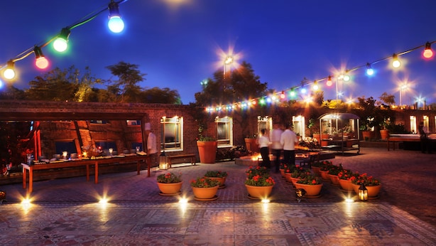 An outdoor patio area with string lights, potted plants, and a brick wall. - Faena Hotel Buenos Aires (Buenos Aires)
