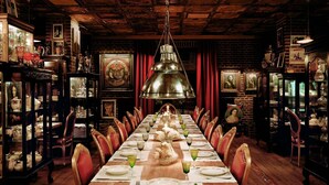 A long dining table set for a meal, surrounded by red chairs, with a chandelier above. - Faena Hotel Buenos Aires (Buenos Aires)