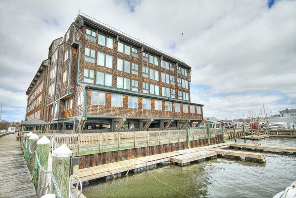 A multi-story building with a dock extending into a body of water, surrounded by other structures. - Club Wyndham Inn on Long Wharf (Newport)