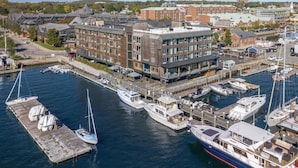 Marina com vários barcos atracados, um edifício com fachada de tijolos e vista clara da cidade ao redor.