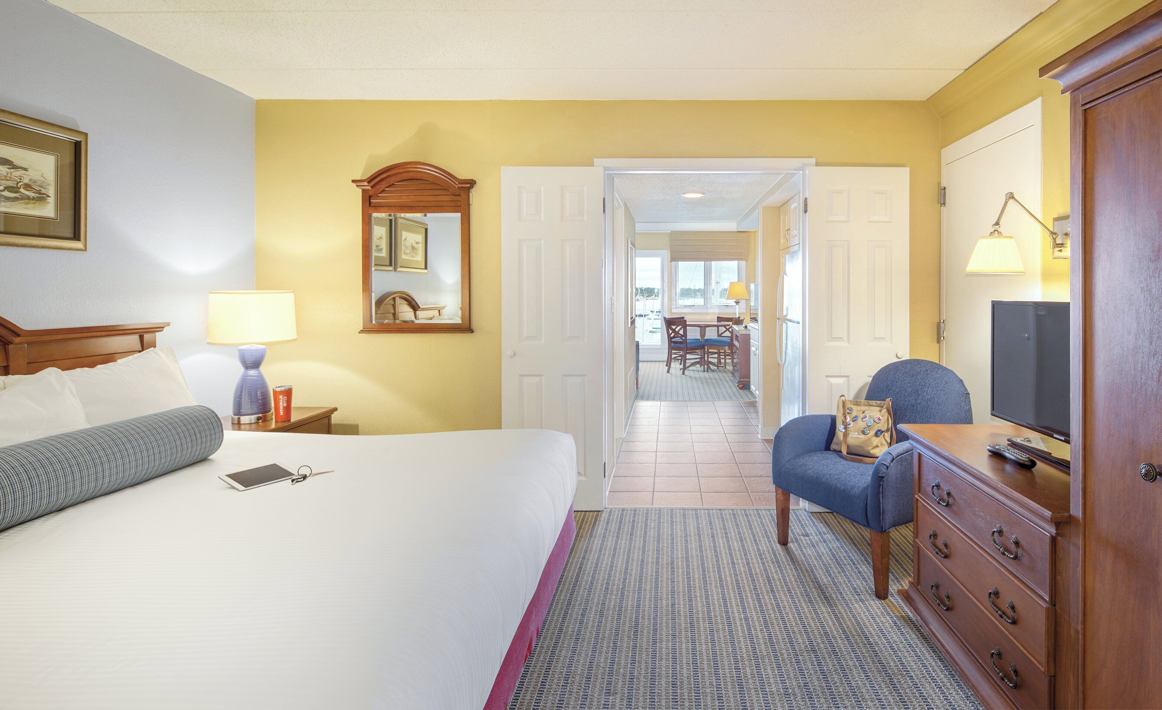 Une chambre d’hôtel comprenant un lit, un bureau, une chaise, une commode et un téléviseur.