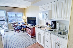 A compact kitchen with white cabinets, a microwave, a coffee maker, and a TV. - Club Wyndham Inn on Long Wharf (Newport)
