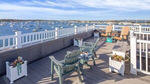 Um deck com cadeiras Adirondack e vista para o porto de iates.