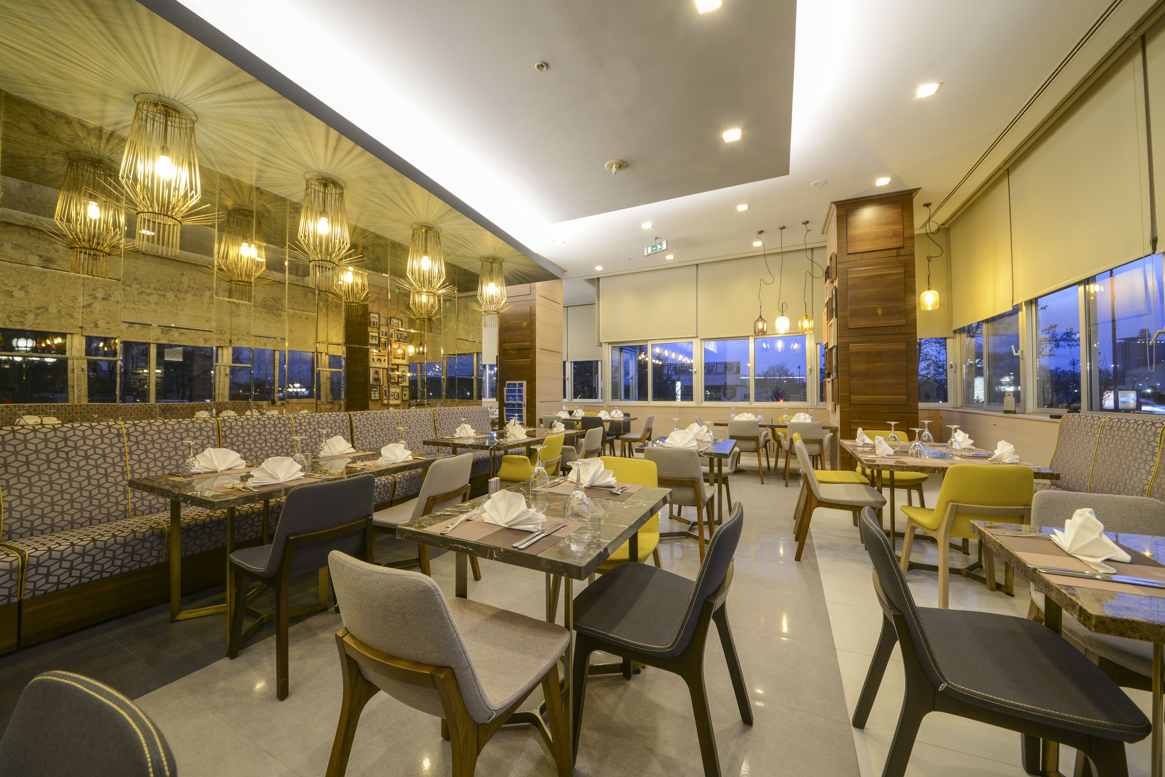 Un ristorante con diverse aree pranzo, tra cui cabine e tavoli, e ampie finestre che offrono viste sulla città di notte.