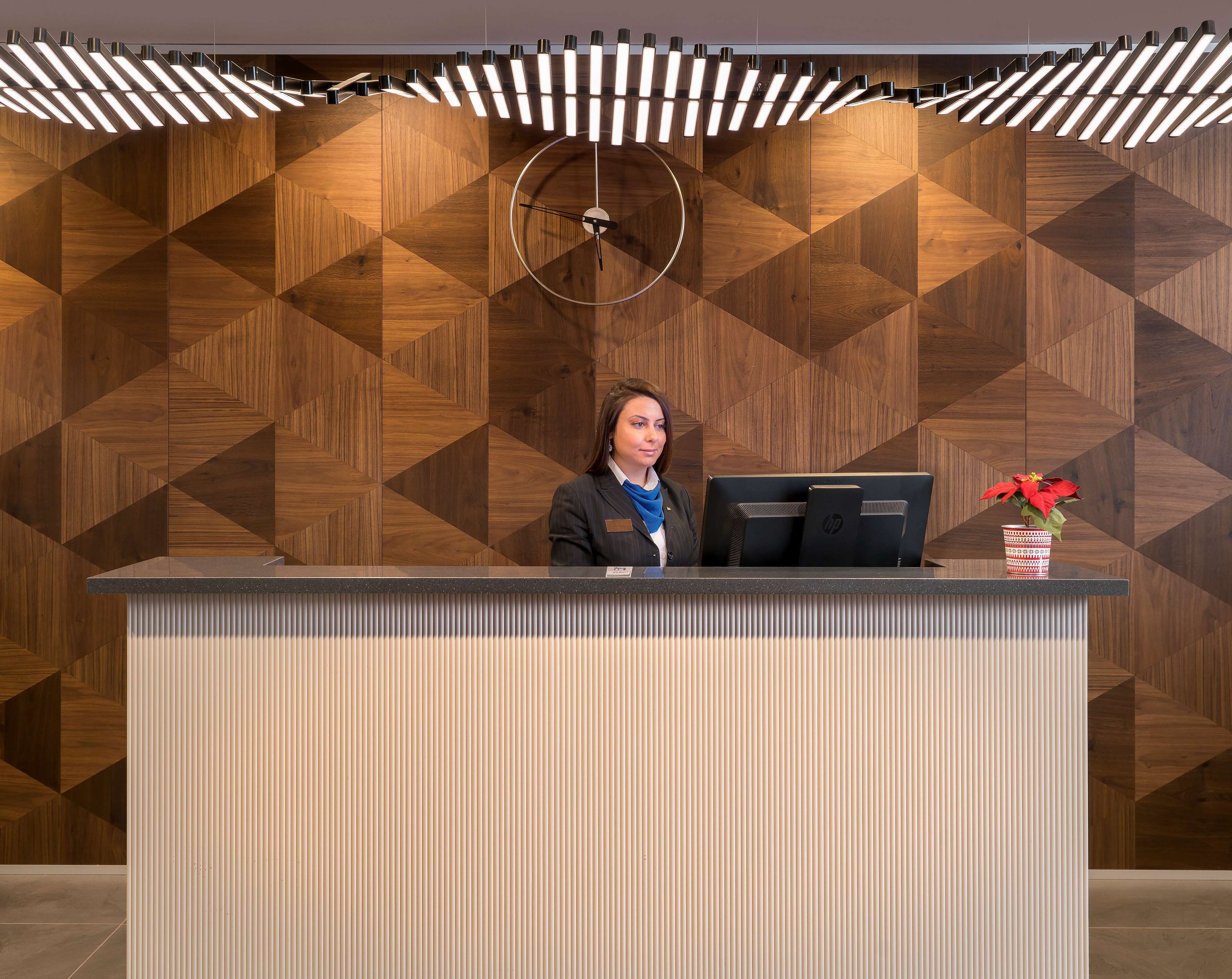 A reception desk with a modern design, a computer, and a potted plant.