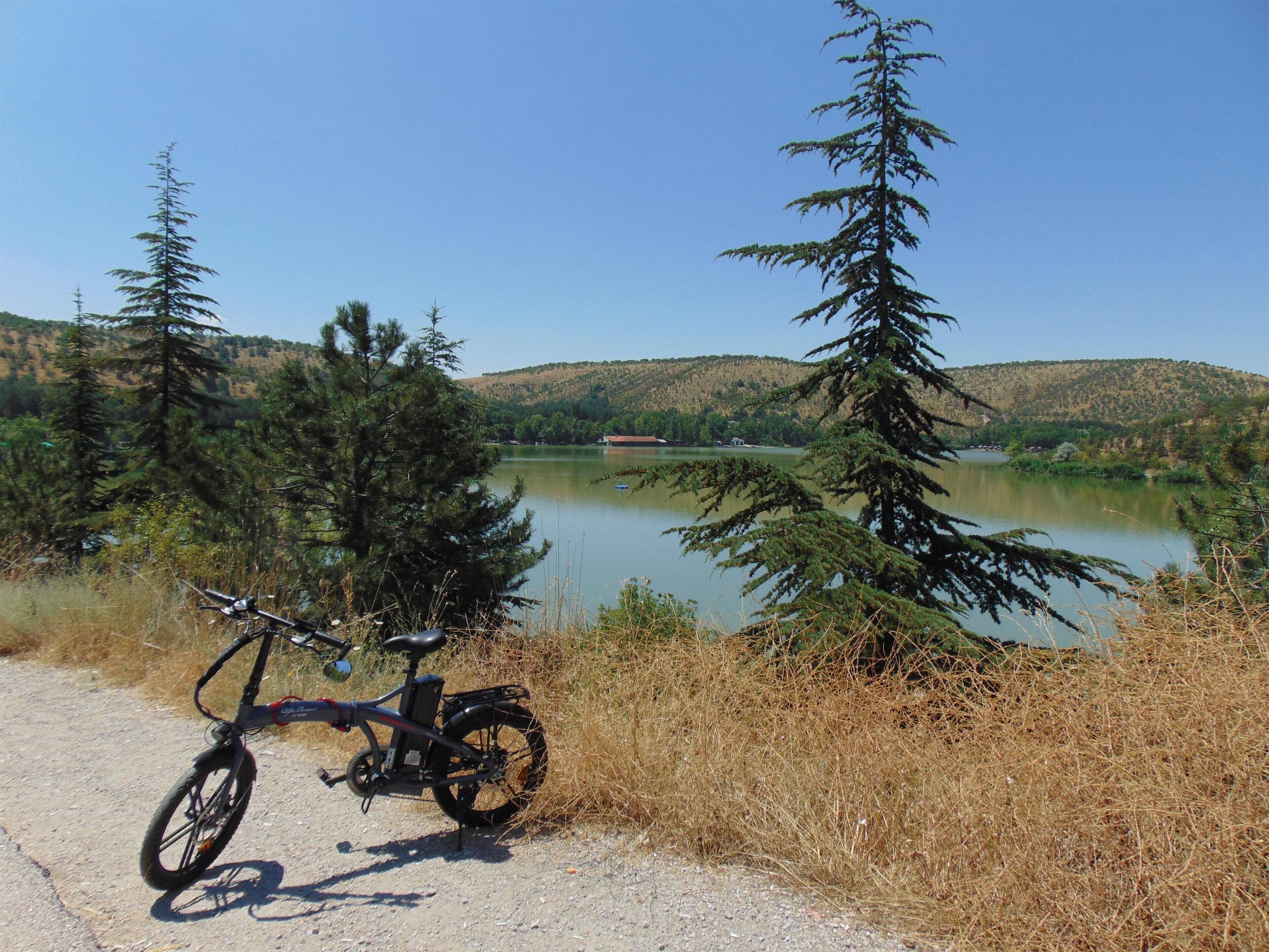 A bicycle parked on a dirt path with a lake and forest in the background.