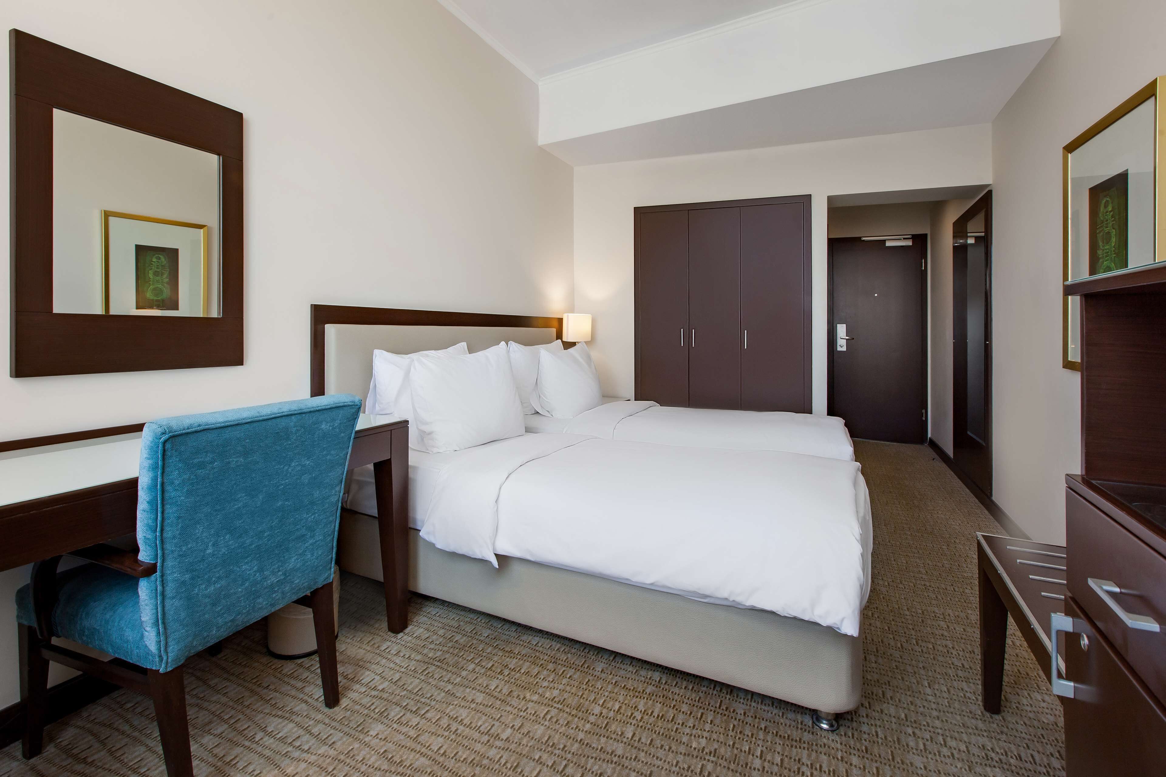 Ein Hotelzimmer mit Bett, Schreibtisch, Stuhl, Kleiderschrank und Spiegel.