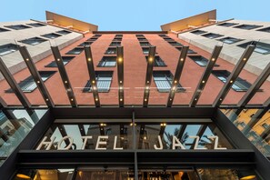 Um hotel com design arquitetônico moderno, apresentando uma placa de destaque 'HOTEL JA 27', grandes janelas e fachada geométrica.