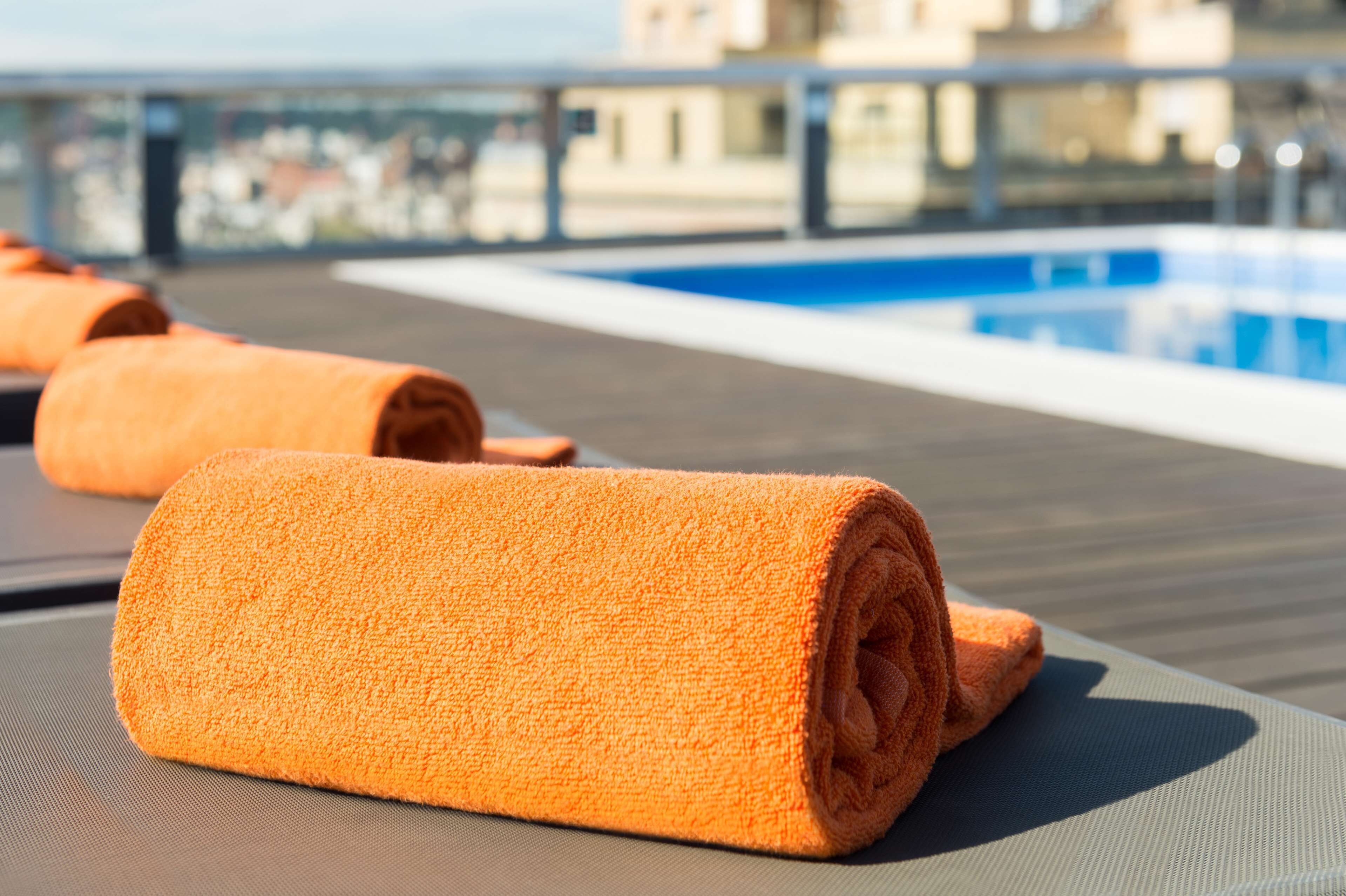 Ein Poolbereich mit orangefarbenen Handtüchern und Blick auf einen Pool.