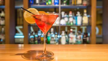 Un cóctel en una copa de martini con una rodaja de limón sobre la barra.