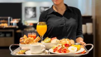 A breakfast tray with various foods and a glass of orange juice.