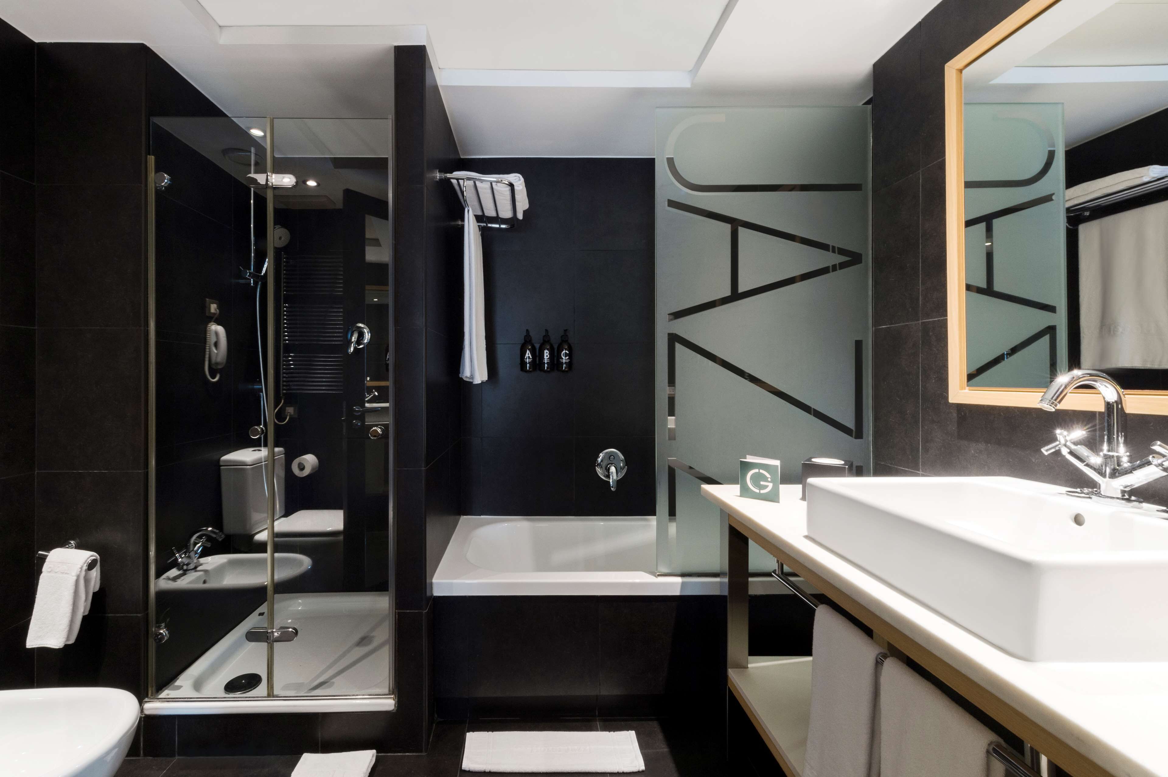 A modern bathroom with a glass-enclosed shower, a large bathtub, a vanity with a mirror, and a toilet.