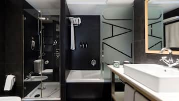 A modern bathroom with a glass-enclosed shower, a large bathtub, a vanity with a mirror, and a toilet.