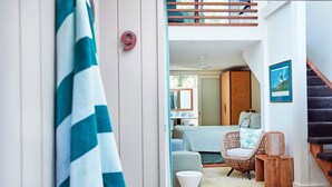 Un intérieur moderne comprenant un lit, une chaise en osier, une petite table et un escalier.