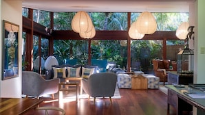 Un vaste espace de vie agrémenté d’une grande fenêtre, de sièges confortables et d’une table basse en bois.