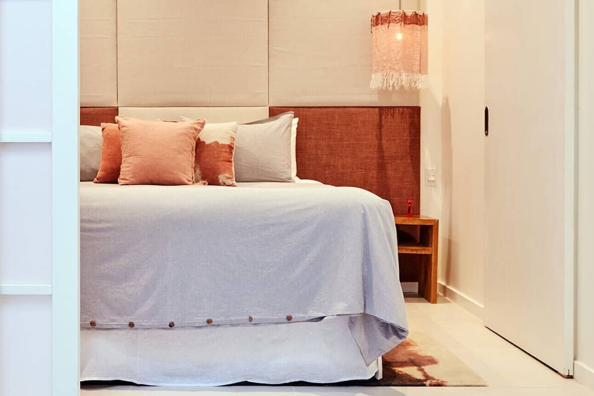 Un dormitorio moderno con cama, mesita de noche y lámpara colgante.