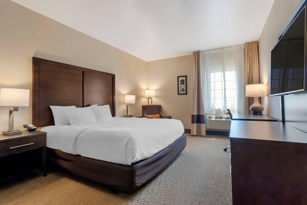 A hotel room with a large bed, bedside tables with lamps, a desk with a flat-screen TV, and a window with curtains. - Comfort Inn & Suites Macon (Macon)