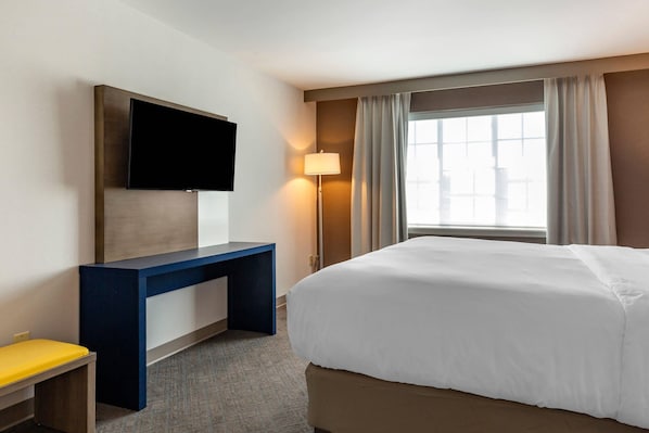 A hotel room with a bed, a desk, a television, and a window with curtains. - Comfort Inn & Suites East Greenbush - Albany (Castleton-on-Hudson)