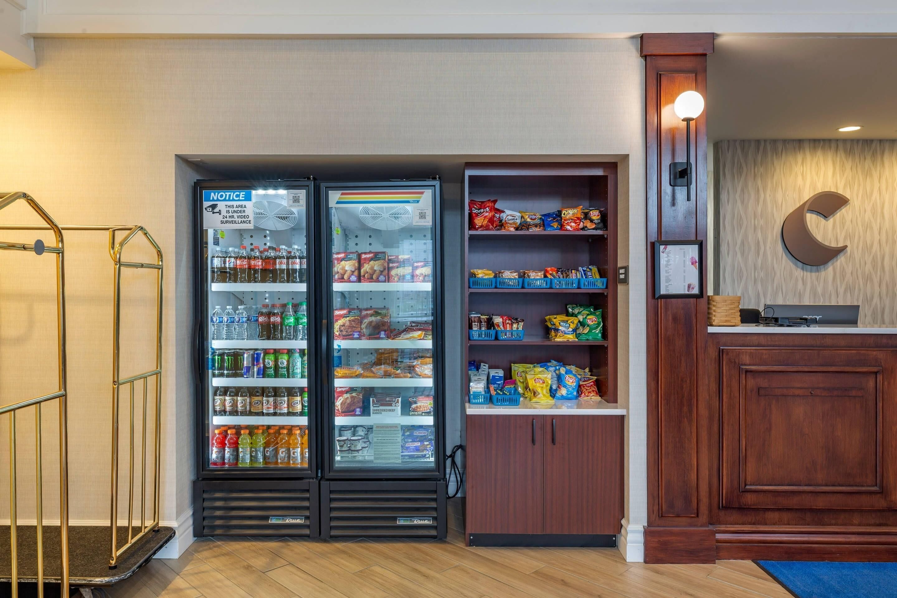 A hotel lobby with a reception desk, a vending machine, and a snack shelf.